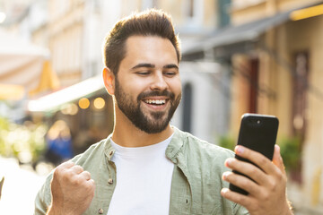 Caucasian young man use mobile smartphone celebrating win good message news, lottery jackpot...