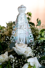 saint statue in the garden, saint statue with flower, religious decoration, white roses, blurred background