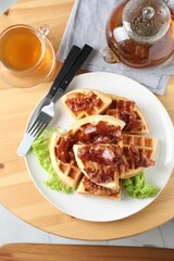 Tasty Belgian waffles served with bacon, lettuce and tea on wooden table, flat lay