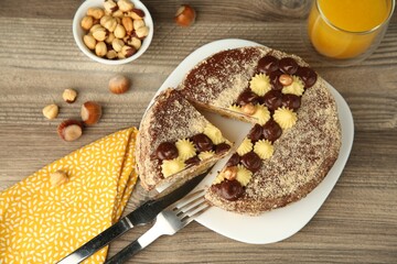 Delicious Kyiv Cake decorated with cream and hazelnuts served on wooden table, above view