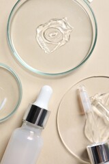 Bottle of cosmetic serum and petri dishes with samples on beige background, flat lay
