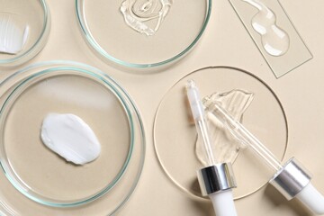 Fototapeta na wymiar Pipettes, cosmetic serum and petri dishes with samples on beige background, flat lay