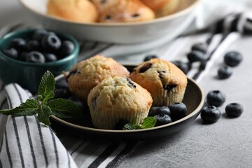 Delicious muffins with blueberries and mint on light grey table, closeup