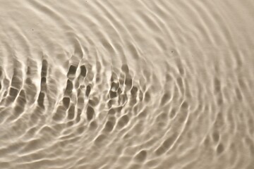 Rippled surface of clear water on beige background, top view