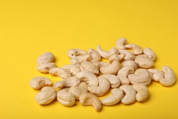 Tasty cashew nuts on yellow background, closeup
