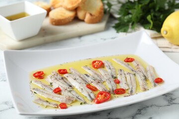 Tasty pickled anchovies with spices on white marble table, closeup