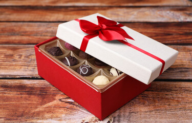 Red box with tasty chocolate candies on wooden table
