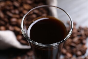 Shot glass of coffee liqueur on blurred background, closeup