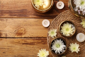 Tibetan singing bowls, beautiful chrysanthemum flowers and burning candles on wooden table, flat lay. Space for text