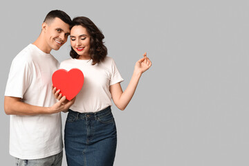 Loving young couple with gift box on grey background. Celebration of Saint Valentine's Day