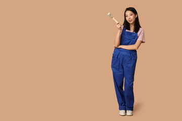 Female Asian happy painter with brush on brown background