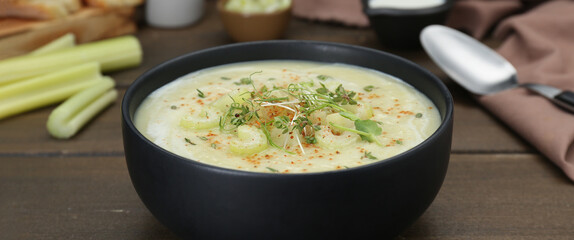 Bowl of delicious celery soup on wooden table, closeup. Banner design