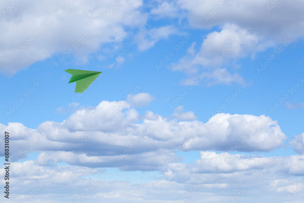 Canvas Prints Green paper plane flying in blue sky with clouds