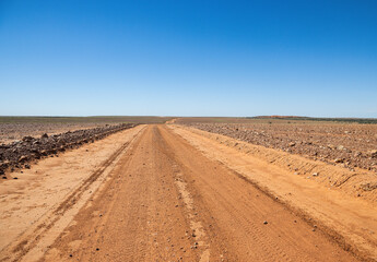 Fototapeta na wymiar A dirt road stretching off into the distance on a Gibber plain in South Australia.
