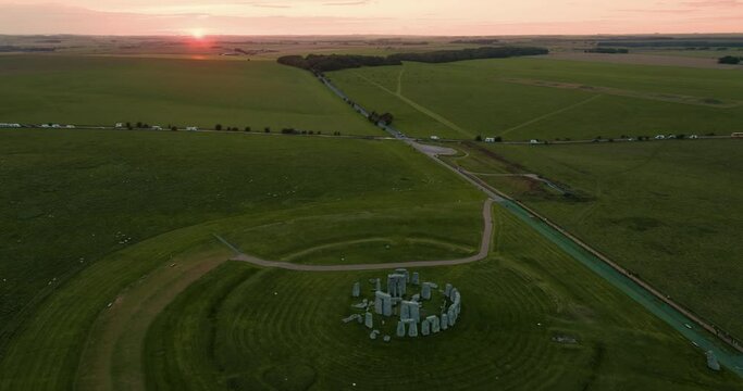 Bird's-eye view of the famous historical monument Stonehenge and green meadows during sunset