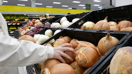 Woman picking fresh onion inside Walmart store