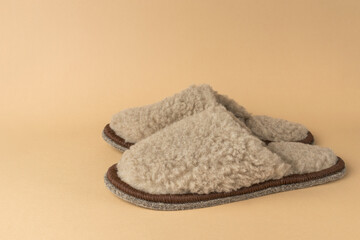 Fototapeta na wymiar Stylish beige slippers made of natural wool on a beige background.
