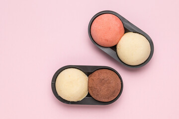 Colorful cakes in plastic containers on a pink background.