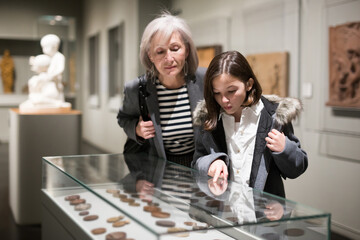 Cute interested preteen girl visiting museum of applied arts with grandmother, exploring ancient...