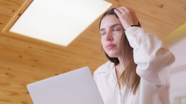 Tired, exhausted woman working on computer laptop, problems with job, feeling depressed, laziness in living room