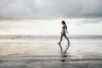 Caucasian woman walking on the beach at sunset