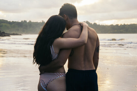Young couple standing on the beach at sunset