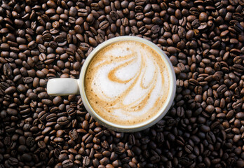 Cafe latte with foam design on a coffee beans background and dramatic light