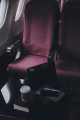 Attractive asian female passenger of airplane sitting in comfortable seat listening music in earphones while working at modern laptop computer with mock up area using wireless connection on board.