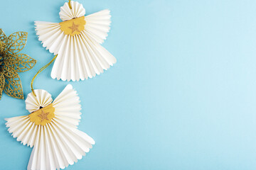 Two white paper angels on blue background. Christmas concept. Top view, flat lay, copy space