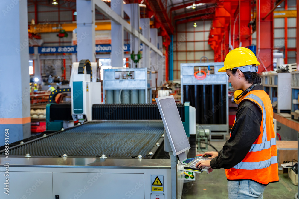 Wall mural engineering technician worker is operating the machine inside factory using touch screen computer mo