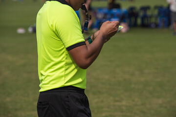 Professional soccer referee on a pitch of a youth soccer tournament. After team scores a goal,...