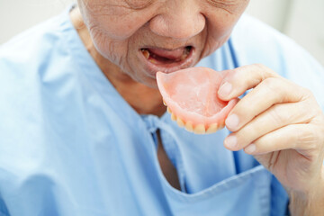 Asian senior woman patient wearing teeth denture into her mouth for chew food.