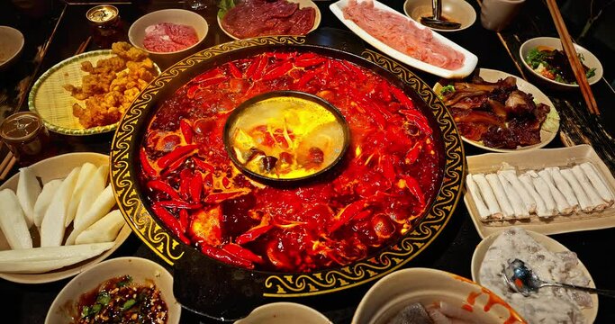 Chinese spicy hot pot cuisine. A layer of red chili pepper floats in the boiling hot pot base. Famous Chongqing Spicy Hot Pot, China.