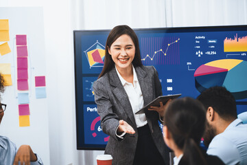 Young asian businesswoman presenting data analysis dashboard on TV screen in modern meeting. Business presentation with group of business people in conference room. Concord