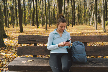 Fototapeta premium Beautiful girl uses phone for fitness or yoga. Body positive, sports for women, harmony, healthy lifestyle, self-love and wellness.