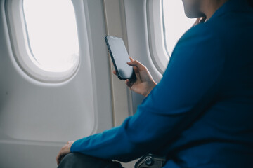 Young Asian business woman talking on smartphone, businesswoman working while flying at plane, Young woman using the internet at airplane, Air travel, long flight.