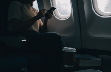 Attractive Asian female passenger of airplane sitting in comfortable seat while working laptop and tablet with mock up area using wireless connection. Travel in style, work with grace.