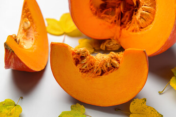 Cut fresh pumpkin and autumn leaves on grey background