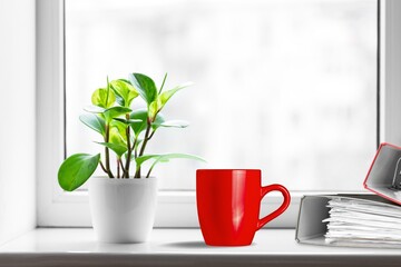 coffee cup on desk, note book by window