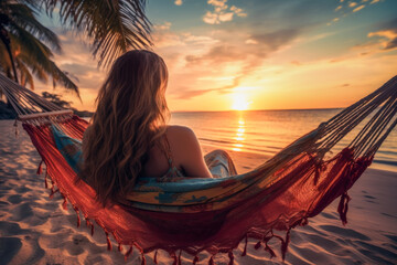 Rear view of a beautiful woman on a hammock on the beach in sunset. Travel concept of vacation and holiday.