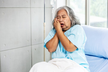 Asian senior woman patients Toothache hurts, touches cheek suffering from sudden tooth pain feels...