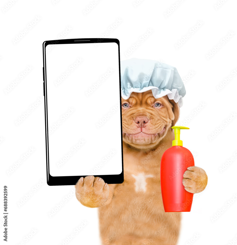 Poster smiling mastiff puppy wearing shower cap holds flea shampoo and big smartphone with white blank scre
