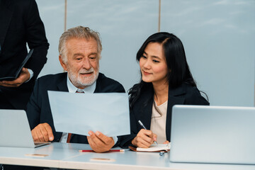 Senior caucasian manager working in office with assistance of young Asian business people and...