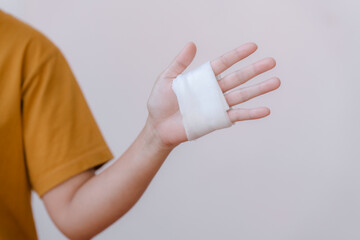 A person in a yellow top has white bandages on their hand and wrist because of a car accident.