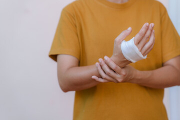 A person in a yellow top has white bandages on their hand and wrist because of a car accident.