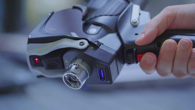 Hand hold futuristic laser scanner and pushes red button. Measure 3D parts - close up.