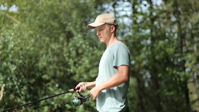 Young male angler stands at edge of forest throw fishing rod, concept of fishing as hobby