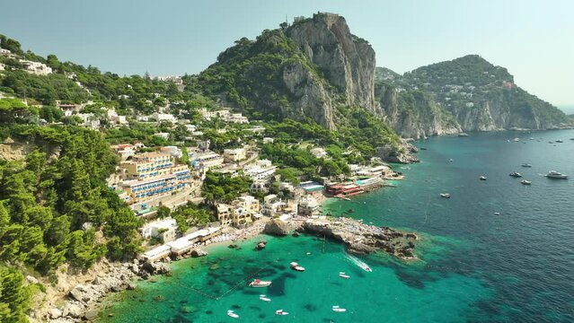 Drone panning shot of gorgeous hotels at Capri Spiaggia di Marina Piccola on a sunny day.
