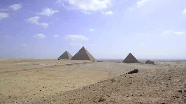 Car crosses landscape of Giza Pyramids in wide shot. Egypt landscape panorama