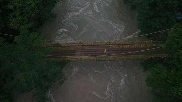 Man walking on yellow bridge over cahabon river at Guatemalan jungle, aerial